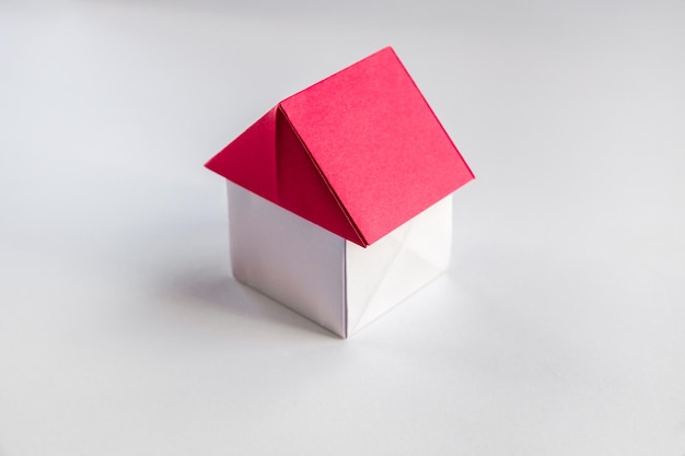 Origami de casa de papel blanco y rojo aislado sobre fondo blanco