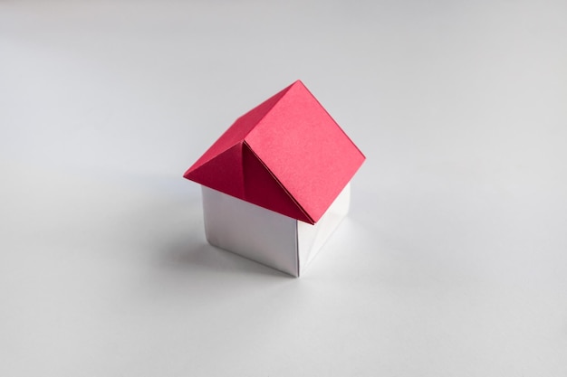 Origami de casa de papel blanco y rojo aislado sobre fondo blanco