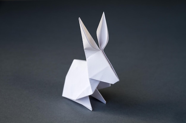 Origami de conejo de papel blanco aislado en un fondo gris