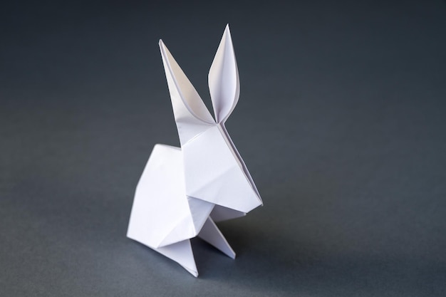 Origami de conejo de papel blanco aislado en un fondo gris