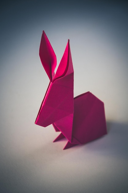 Foto origami de conejo de papel rosa aislado sobre fondo blanco