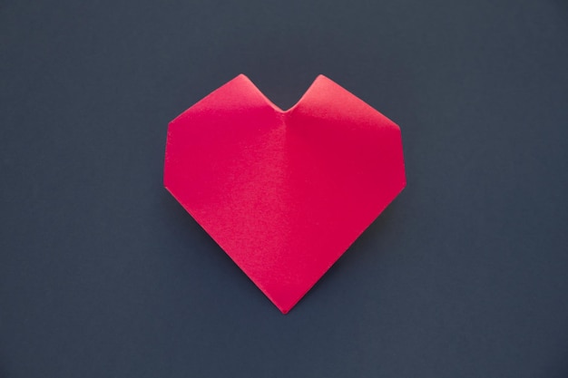 Origami de corazón de papel rojo aislado sobre un fondo gris