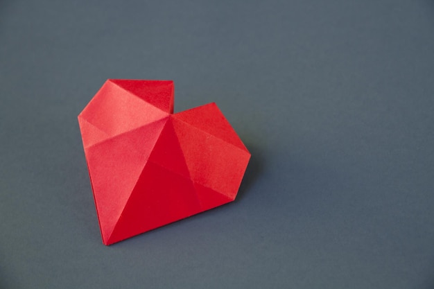 Origami de corazón de papel rojo aislado sobre un fondo gris