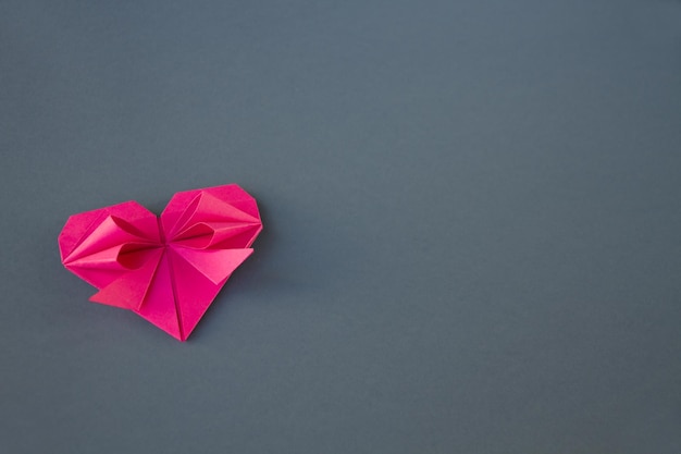 Origami de corazón de papel rosa aislado sobre un fondo gris