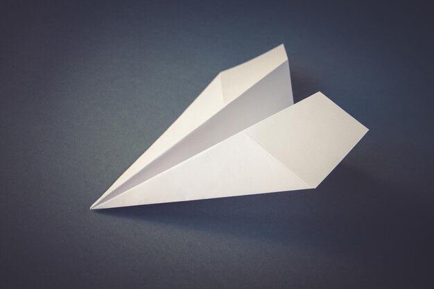 Foto origami de avião de papel branco isolado em um fundo cinza