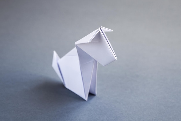 Origami de cachorro de papel branco isolado em um fundo cinza