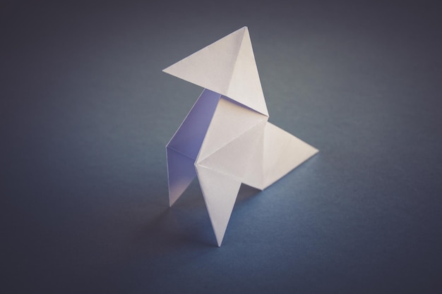 Origami de galinha de papel branco isolado em um fundo cinza