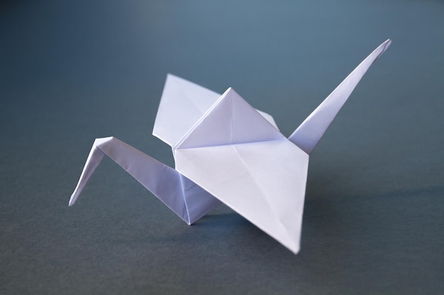 Origami de guindaste de papel branco isolado em um fundo cinza