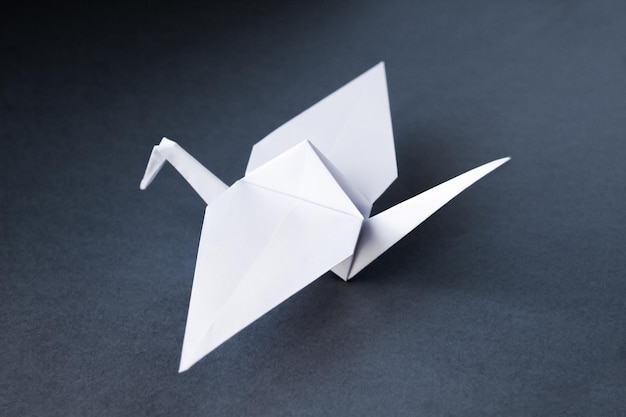 Origami de guindaste de papel branco isolado em um fundo cinza