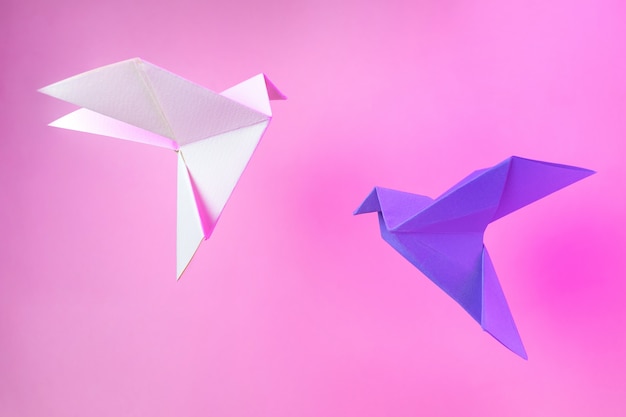 Origami de papel duas pombas em um rosa pastel