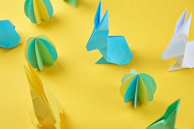Origami de papel esater coelhos e ovos coloridos em uma parede amarela conceito de celebração da Páscoa