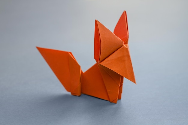 Origami de raposa de papel laranja isolado em um fundo cinza