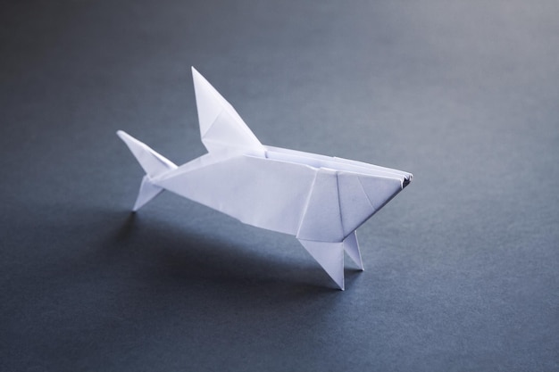 Origami de tubarão de papel branco isolado em um fundo cinza