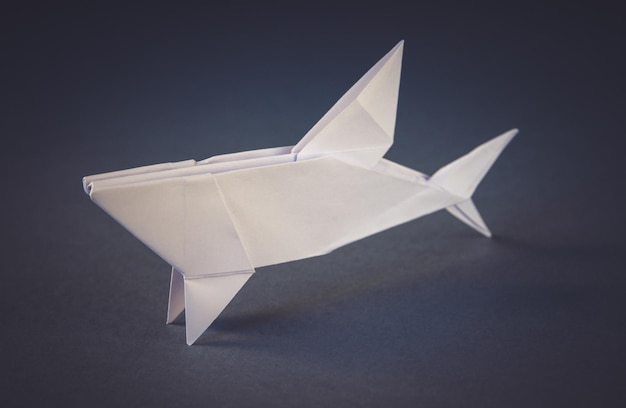 Origami de tubarão de papel branco isolado em um fundo cinza