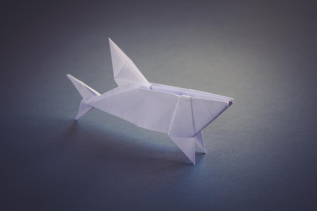 Origami de tubarão de papel branco isolado em um fundo cinza