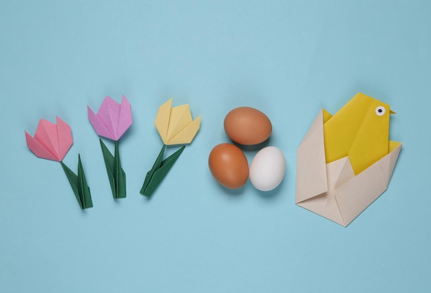 Origami Hühnereier und Tulpen auf blauem Hintergrund Frühling Ostern Konzept