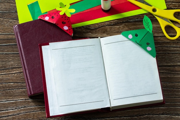 Origami de un marcador de papel para libros una fresa y una manzana sobre una mesa de madera