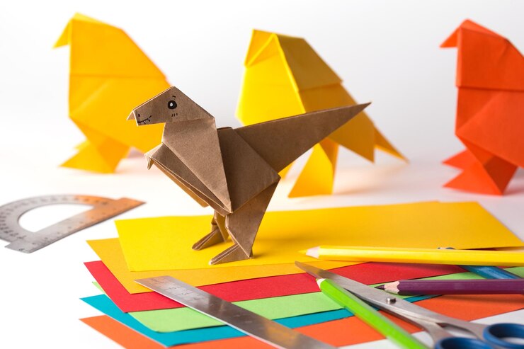 Foto origami pájaro y dinosaurio hechos de papel de colores papel regla lápices cuchillo interesante pasatiempo