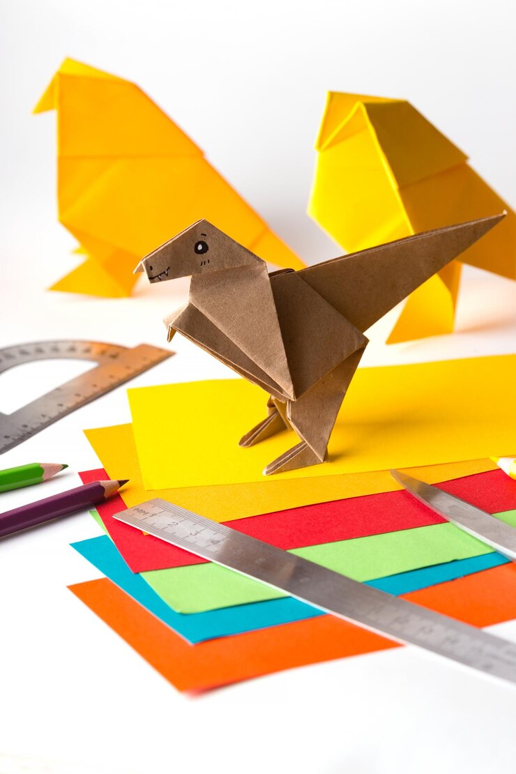 Foto origami pájaro y dinosaurio hechos de papel de colores papel regla lápices cuchillo interesante pasatiempo