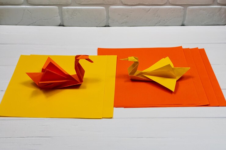 Foto origami papel laranja e cisnes amarelos em um fundo branco uma reunião vista lateral criatura