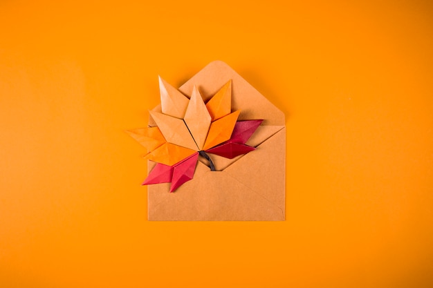 Origami papercraft outono conceito folhas caídas carta em um envelope em uma arte de artesanato artesanal de fundo laranja