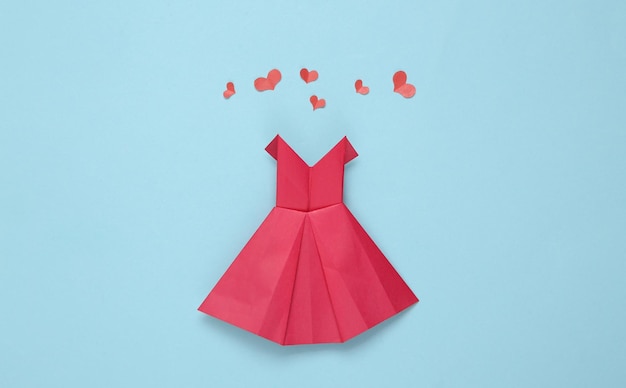 Origami-Papier rotes Kleid mit Herzen auf blauem Hintergrund