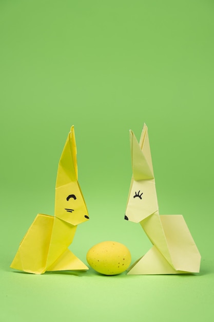 Origami de Pascua dos conejitos de papel y un fondo verde huevo