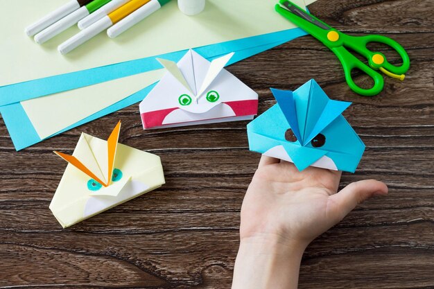 Foto origami-spielzeug aus papier, wütender vogel, klebemesser und papier auf einem holztisch