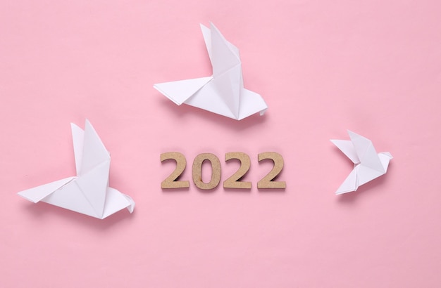 Origami-Tauben und 2022 auf rosa Hintergrund Friedenssymbol