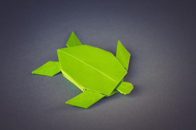 Origami de tortuga de papel verde aislado sobre un fondo gris