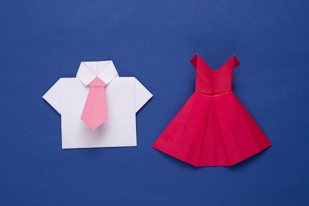 Origami vestido rojo hecho a mano y camisa con corbata sobre fondo azul.