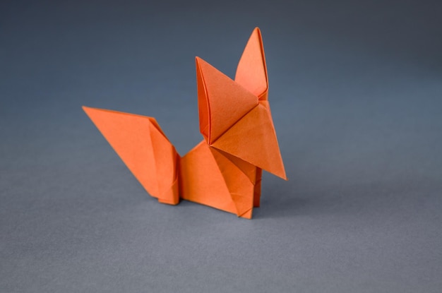 Origami de zorro de papel naranja aislado en un fondo gris