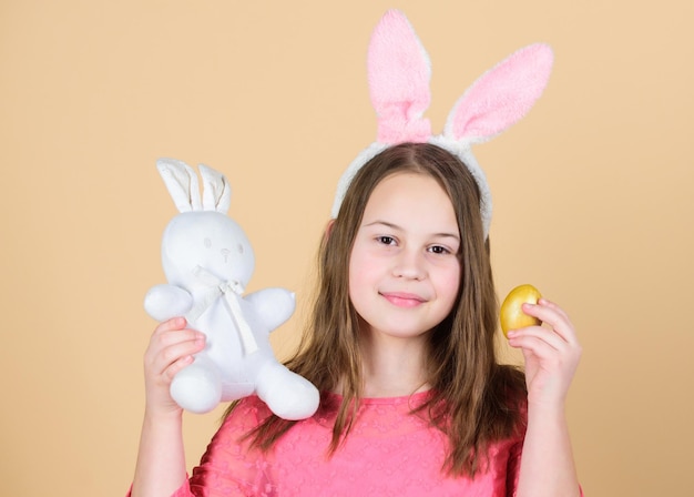 Origen del conejito de Pascua Símbolos y tradiciones de Pascua Niño juguetón con peluche Conoce las vacaciones de primavera Caza de huevos de Pascua como parte del festival Niña pequeña accesorio de conejito de Pascua sujetar huevo teñido