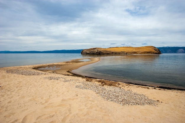 La orilla arenosa del lago Baikal con vistas a la arena y la isla