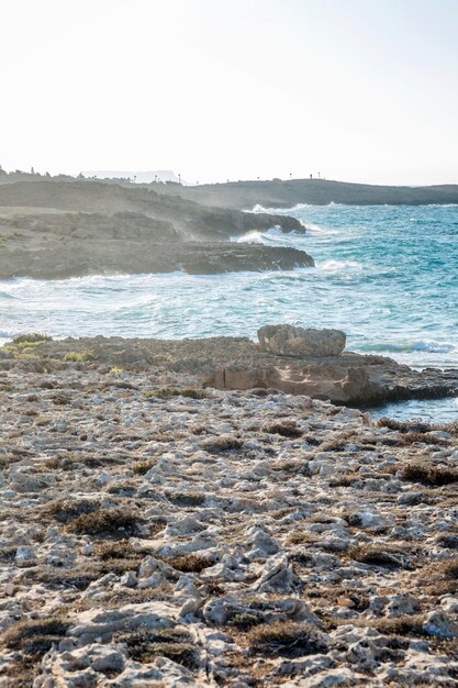 Orilla rocosa del mar turquesa contra un cielo azul claro al amanecer Hermoso paisaje y relajación Vertical