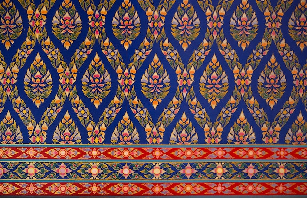 Ornamento de arte de estilo tailandés papel tapiz de patrón sin costuras representa fondo floral diseño rojo, azul, verde y amarillo en la pared en un templo en Tailandia