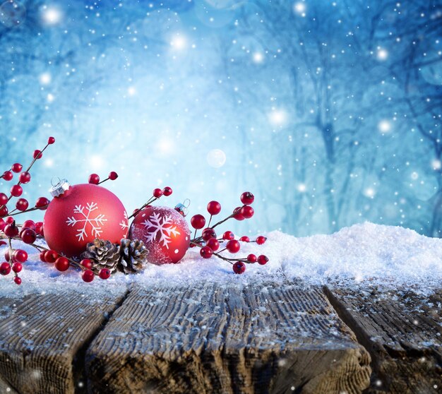 Foto ornamento de natal vermelho em mesa de neve com neve em fundo