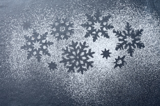 Foto ornamento de polvo de azúcar de copo de nieve en pizarra negra