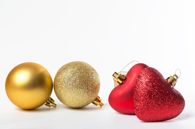Ornamentos para as bolas douradas da árvore de Natal de diferentes texturas e um coração vermelho