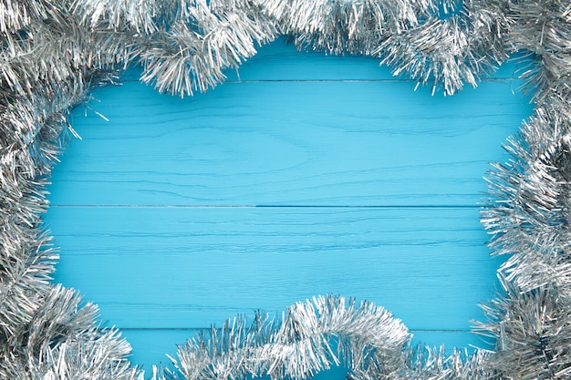 Oropel de plata de Navidad sobre fondo de madera azul. Esto tiene trazado de recorte. Vista superior.