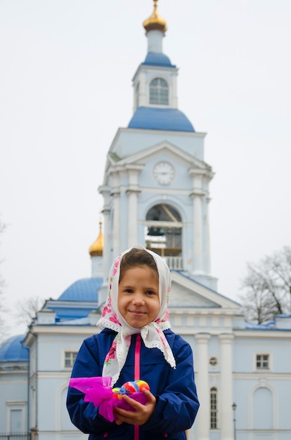 Orthodoxe Ostern. Mädchen mit farbigen Ostereiern über der Kirche