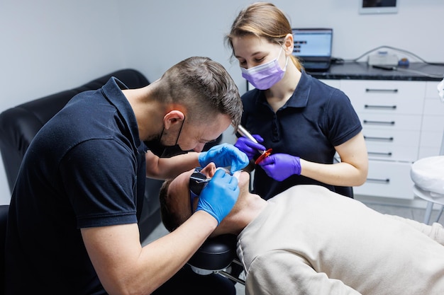 Un ortodoncista con un asistente trata los dientes usando instrumentos dentales Consultorio dental Tratamiento de ortodoncia de los dientes