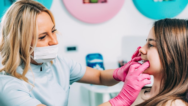 Ortodoncista comprobando los aparatos dentales de la niña