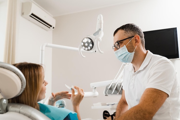 El ortodoncista muestra un protector bucal para blanquear los dientes en odontología El dentista consulta a la paciente sobre el procedimiento de blanqueamiento dental en el hogar