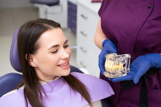 El ortodontista explica al paciente el procedimiento de alineación de los dientes utilizando un diseño de mandíbula en