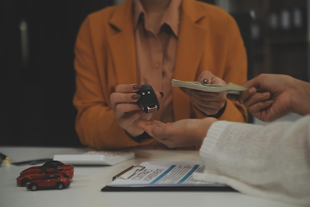 Os agentes de seguros entregam as chaves do carro depois que o inquilino assinou um documento de seguro de automóvel ou um documento de arrendamento ou acordo de compra ou venda de um carro novo ou usado com um carro