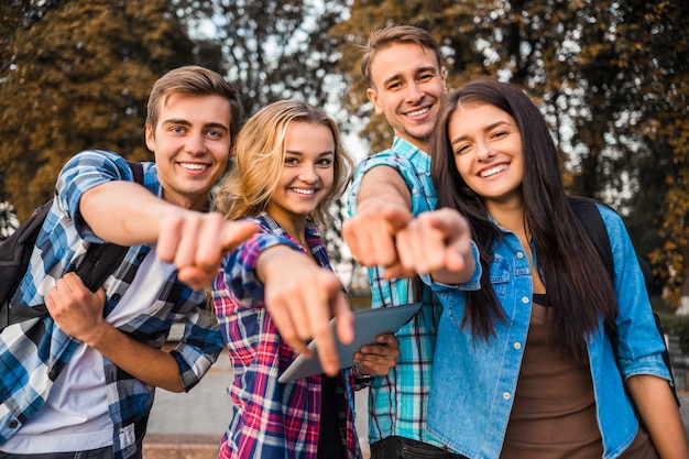 Os alunos apontam para a câmera e sorriem.