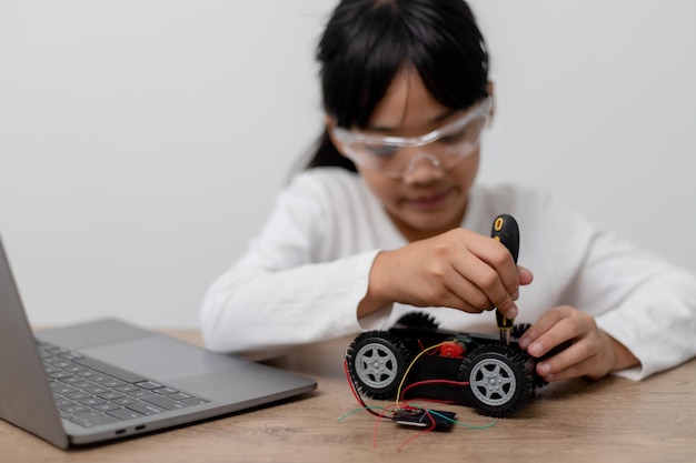 Os alunos da Ásia aprendem em casa na codificação de carros robóticos e cabos de placas eletrônicas em STEM STEAM matemática engenharia ciência tecnologia código de computador em robótica para crianças conceito