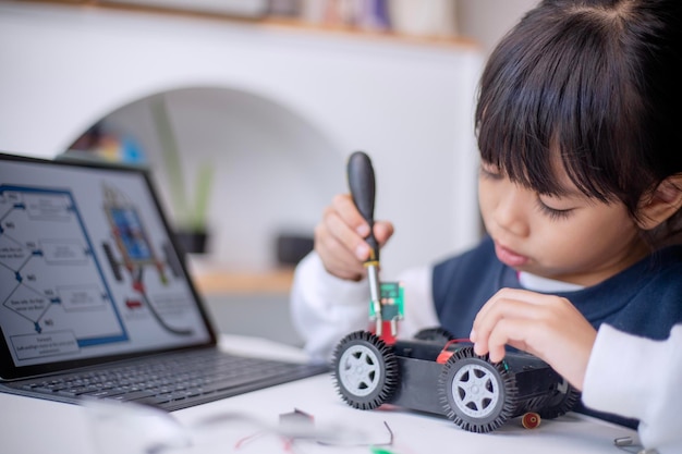 Os alunos da Ásia aprendem em casa na codificação de carros robóticos e cabos de placas eletrônicas em STEM STEAM matemática engenharia ciência tecnologia código de computador em robótica para crianças conceito