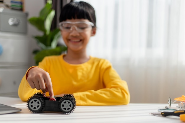 Os alunos da Ásia aprendem em casa na codificação de carros robóticos e cabos de placas eletrônicas em STEM STEAM matemática engenharia ciência tecnologia código de computador em robótica para crianças conceito